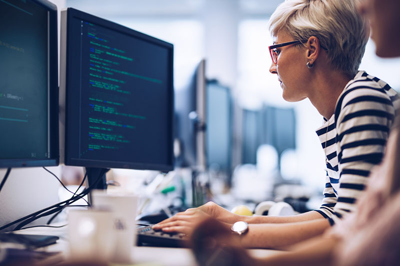 A woman writes code on a computer